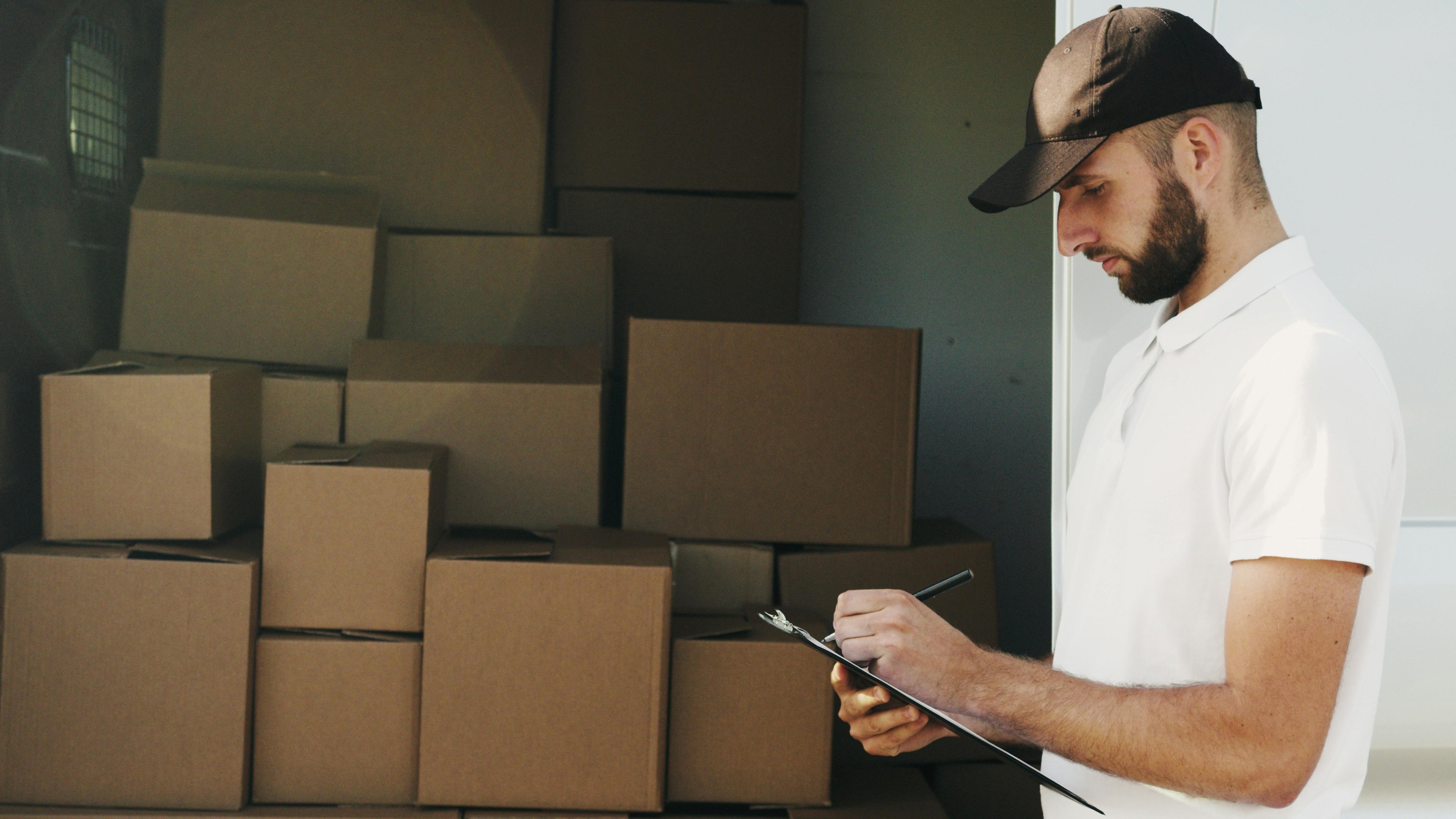 Man checking a list next to stacked cardboard boxes